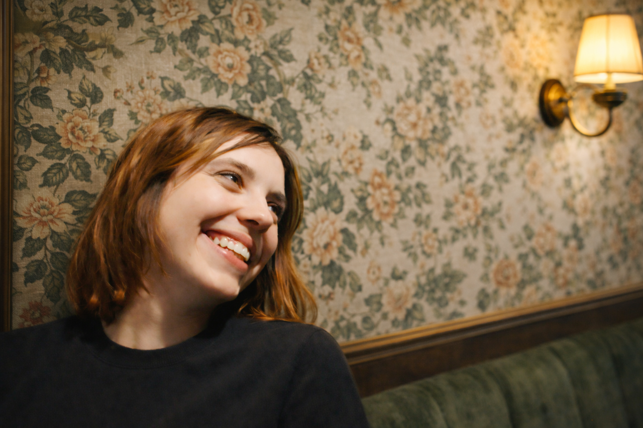 Lächelnde frau vor Blumentapete